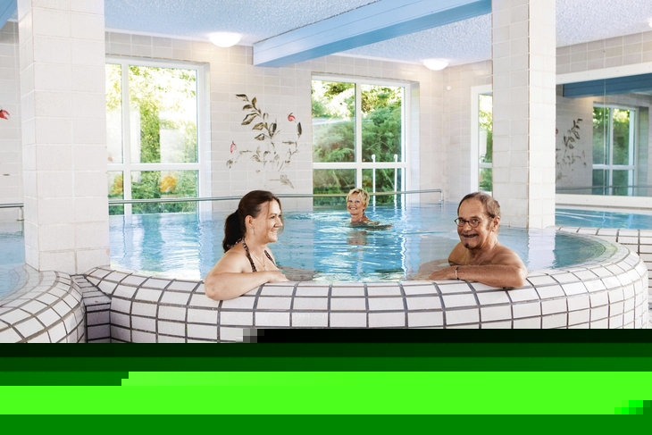 Personen entspannen im Innenpool eines Thermalbads.