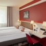 Doppelzimmer im Best Western Hotel Leipzig mit zwei Betten und roter Wand.