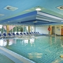 Innenpool des Ahorn Panorama Hotel Oberhof mit blauen Liegestühlen und großen Fenstern.
