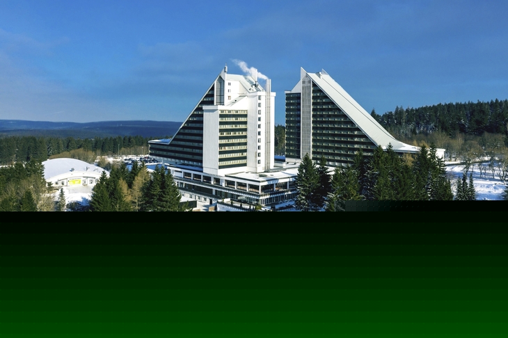 Ahorn Panorama Hotel Oberhof im Winter, umgeben von verschneiten Bäumen.