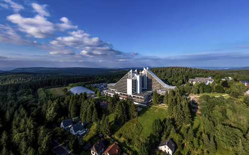 Außenansicht des Ahorn Panorama Hotel Oberhof im Sommer, umgeben von Wald.