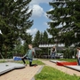 Familie spielt Minigolf im Freien, umgeben von Bäumen.