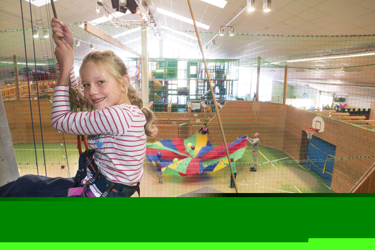 Mädchen klettert an einem Kletterturm in einem Indoor-Freizeitpark.