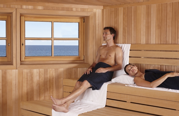Ein Mann und eine Frau entspannen in einer Sauna mit Meerblick.