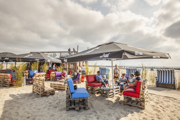 Strandlounge mit Sitzgelegenheiten aus Paletten und Sonnenschirmen am Ostseestrand.