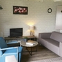 Wohnzimmer mit Sofa, Sessel, TV und Lampe auf Holzfußboden.