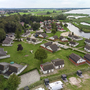 Luftaufnahme eines Ferienparks am Wasser mit vielen kleinen Häusern und Bäumen.