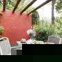 Terrasse mit Tisch, Stühlen und gedecktem Frühstück in grünem Garten.