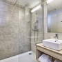 Modernes Badezimmer mit Dusche, Waschtisch, Handtüchern und Haartrockner