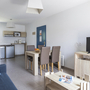 Wohnzimmer in Ferienwohnung mit Sofa, Esstisch, Fernseher und Mini-Küche.