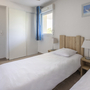 Helles Schlafzimmer mit zwei Einzelbetten, Nachttischlampen und einem Fenster.
