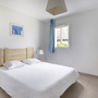 Modernes Schlafzimmer mit Doppelbett, weißen Wänden und blauem Vorhang.