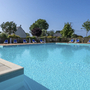 Poolbereich mit Liegestühlen in einer Ferienanlage bei sonnigem Wetter.