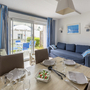 Essbereich und Wohnzimmer einer modernen Ferienwohnung mit gedecktem Tisch und Balkonblick.