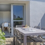 Terrasse mit Esstisch und Stühlen vor einem Ferienhaus.