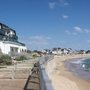 Küstenlandschaft mit Gebäuden am Strand und blauem Himmel.
