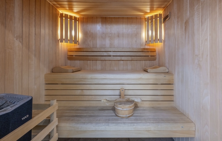 Holzsauna mit beleuchteten Elementen und einem Eimer auf der Bank.