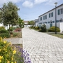 Gepflegter Gartenweg zwischen weißen Gebäuden mit grünen Fensterläden