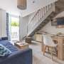 Wohnbereich mit Sofa, Esstisch und Treppe in modernem Ferienapartment.