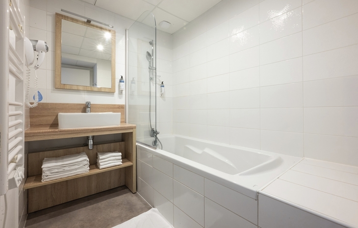 Modernes Badezimmer mit Badewanne, großem Spiegel und Holzdetails.