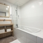 Modernes Badezimmer mit Badewanne, großem Spiegel und Holzdetails.