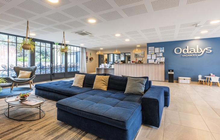 Lounge-Bereich einer modernen Ferienresidenz mit Sofas und Empfangstresen.
