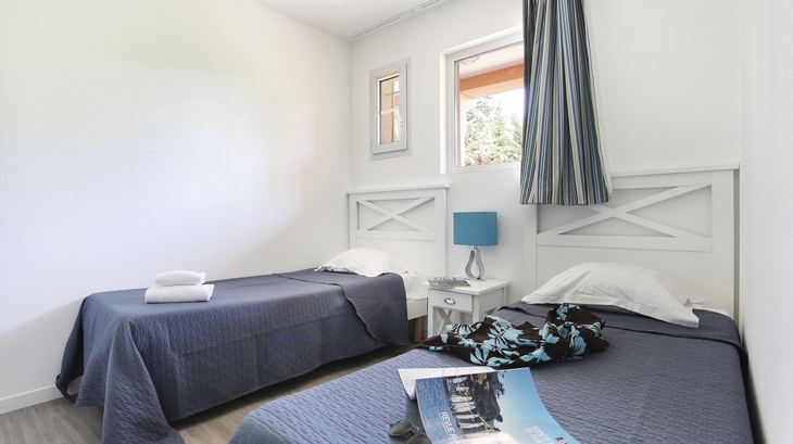 Zwei Einzelbetten in einem hellen Zimmer mit blauem Dekor.