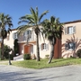 Haus im mediterranen Stil mit Palmen und Garten im Vordergrund.