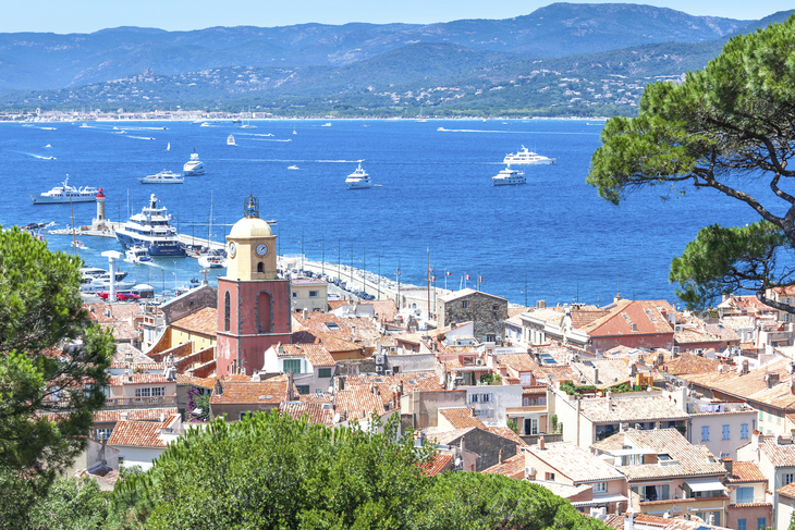 Blick auf Saint-Tropez mit Booten im blauen Meer und Hügel im Hintergrund.