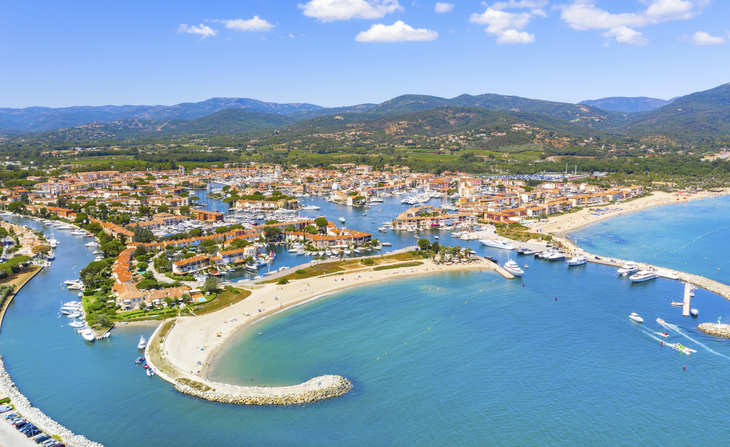 Luftaufnahme von Port Grimaud mit Wasserstraßen und Booten unter blauem Himmel.