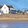 Mehrere Gebäude am Strand von Trégastel unter blauem Himmel.
