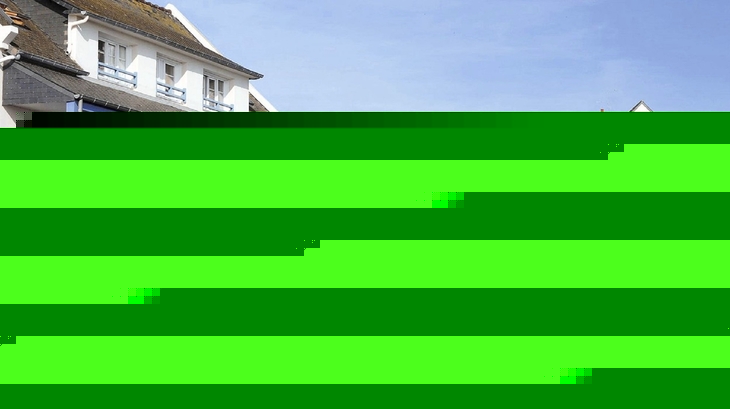 Wohnanlage mit weißen Gebäuden, blauen Balkonen und einem Garten im Vordergrund.
