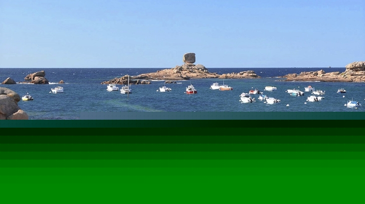 Strand mit Felsen, im Wasser mehrere Boote, Menschen am Strand.