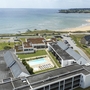 Luftaufnahme einer Ferienresidenz mit Pool nahe am Strand.