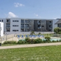 Wohnanlage mit Pool und Liegestühlen im Freien vor modernen Gebäuden.