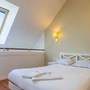 Helles Schlafzimmer mit Doppelbett, Dachfenster und Nachttischen.