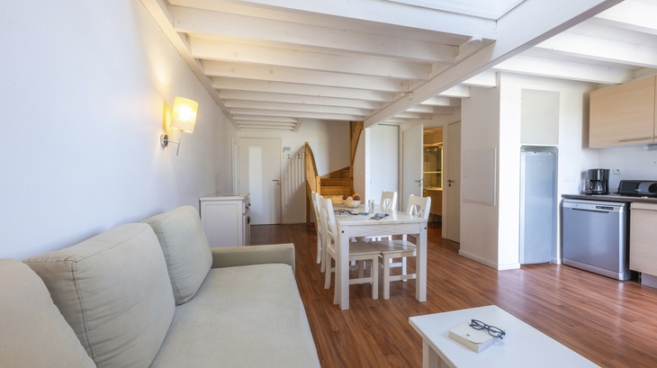Helles Wohnzimmer mit Esstisch, Sofa und Küchenzeile.
