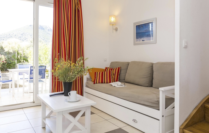 Wohnzimmer mit Sofa, Couchtisch und Blick auf Terrasse.