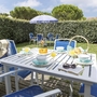 Garten mit Tisch, Stühlen, Sonnenschirm und Frühstücksgedeck im Freien.