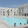 Außenansicht eines modernen Hotels mit Pool und Sonnenliegen.