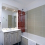 Modernes Badezimmer mit Badewanne, Spiegel und Wandkacheln.