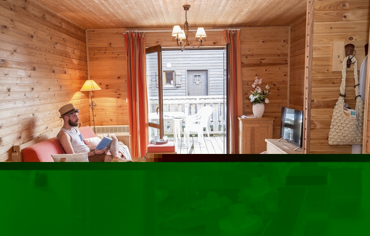 Wohnzimmer in holzvertäfeltem Chalet, mit Möbeln und Balkonzugang.