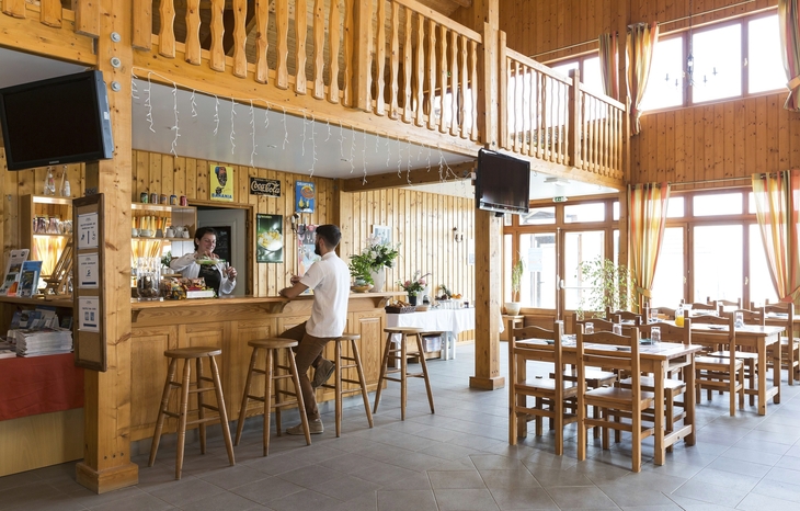 Holzinterieur eines Restaurants mit Bar, Tischen und Stühlen.