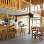 Holzinterieur eines Restaurants mit Bar, Tischen und Stühlen.