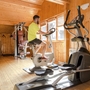 Mann trainiert auf Heimtrainer in holzgetäfeltem Fitnessraum.