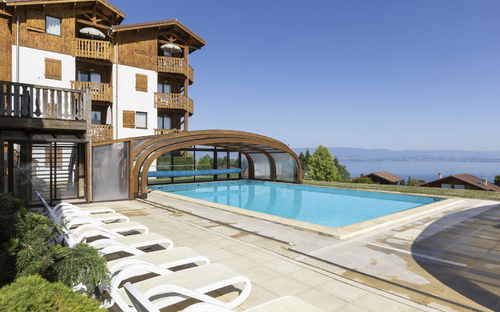 Außenpool mit Liegestühlen vor einem Chalet mit Blick auf den See und Berge im Hintergrund.