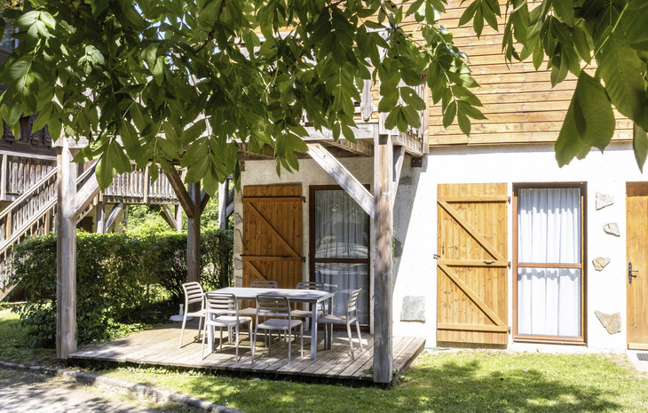 Terrasse eines Chalets mit Gartentisch und Stühlen im Grünen