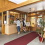 Rezeption in einer Holzlobby mit Gästen und Informationsmaterial.