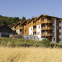 Appartementgebäude mit Balkonen in hügeliger, bewaldeter Landschaft.
