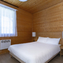 Schlafzimmer in einem Chalet mit Doppelbett und Holzwänden.